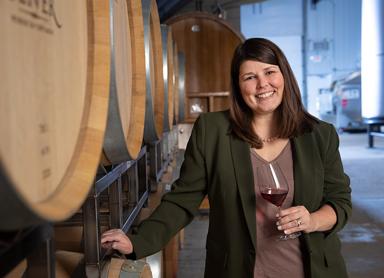 Marketing Director Sarah Anderson poses by barrels in the wine cellar at Oliver Winery in Bloomington, Indiana.